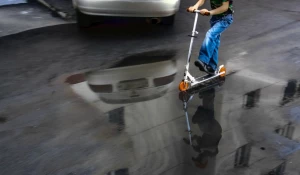 Мальчик катится по луже.