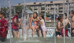 Жара, дети купаются в фонтане.