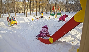 Дети играют в снегу на детской площадке.