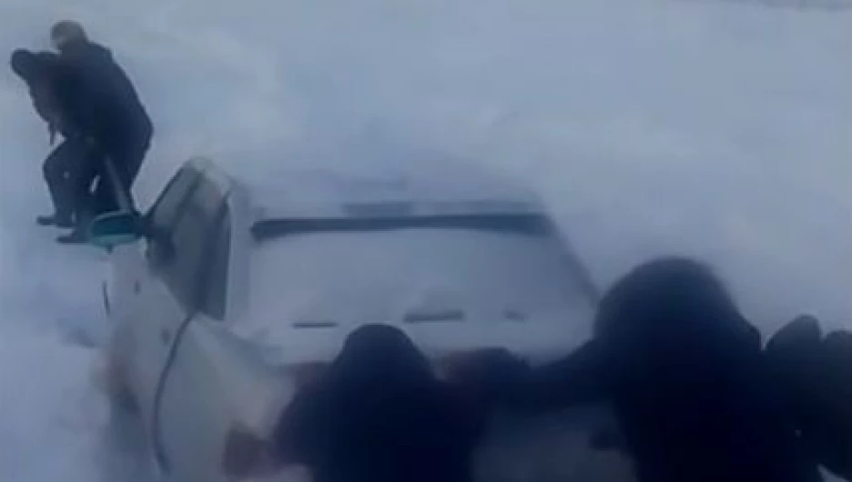 Люди вызволяют застрявшую в снегу машину в Усть-Канском районе.