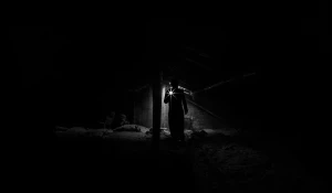 Мужчина с фонариком в темноте.