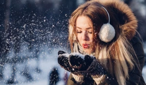 Женщина сдувает снег.