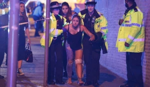 Полицейские ведут пострадавшую от взрыва на стадионе Манчестера. 22 мая 2017 года