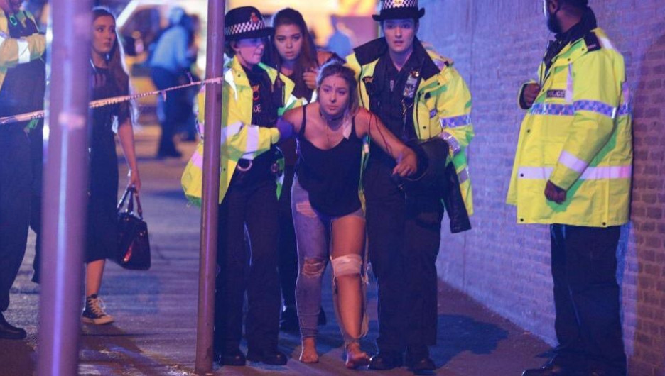 Полицейские ведут пострадавшую от взрыва на стадионе Манчестера. 22 мая 2017 года