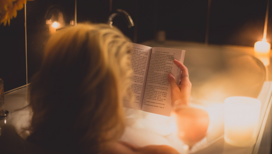 Девушка в ванне читает книгу.