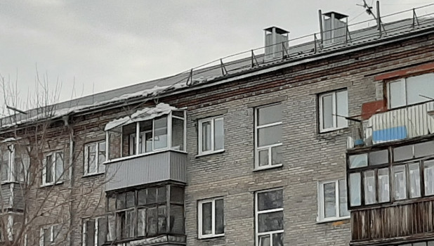 Ограждение упало с крыши дома и висело, зацепившись за балкон. Барнаул.