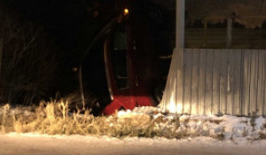 Красный автомобиль протаранил забор и врезался в жилой дом.