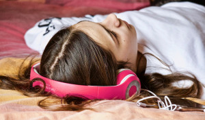 Девушка лежит и слушает музыку.