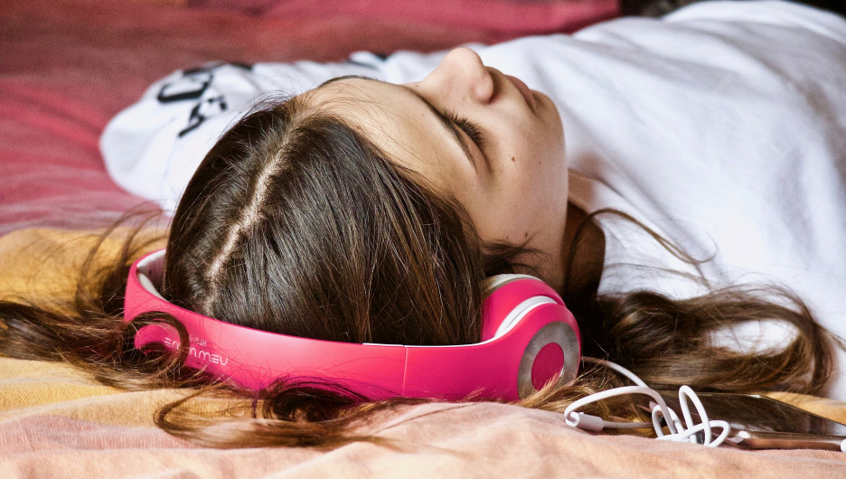 Девушка лежит и слушает музыку.
