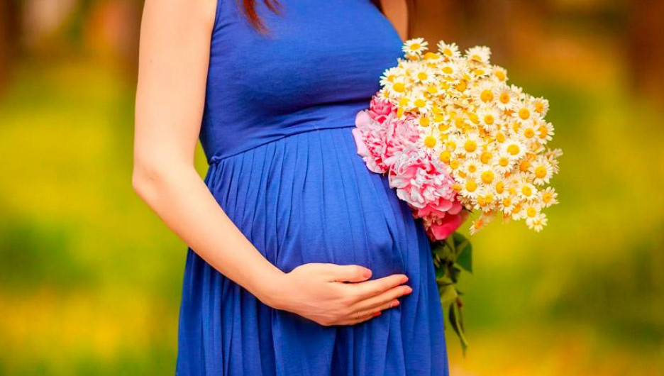 Беременная женщина с букетом цветов.