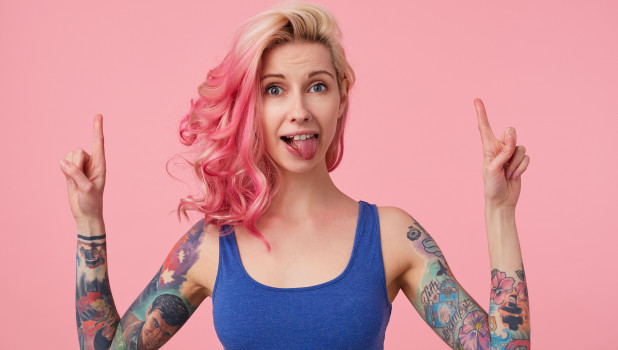 Девушка с розовыми волосами и татуировками.
