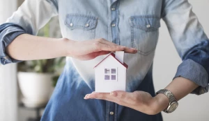 Девушка держит игрушечный домик.