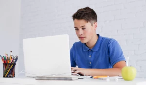 Мальчик работает за ноутбуком.