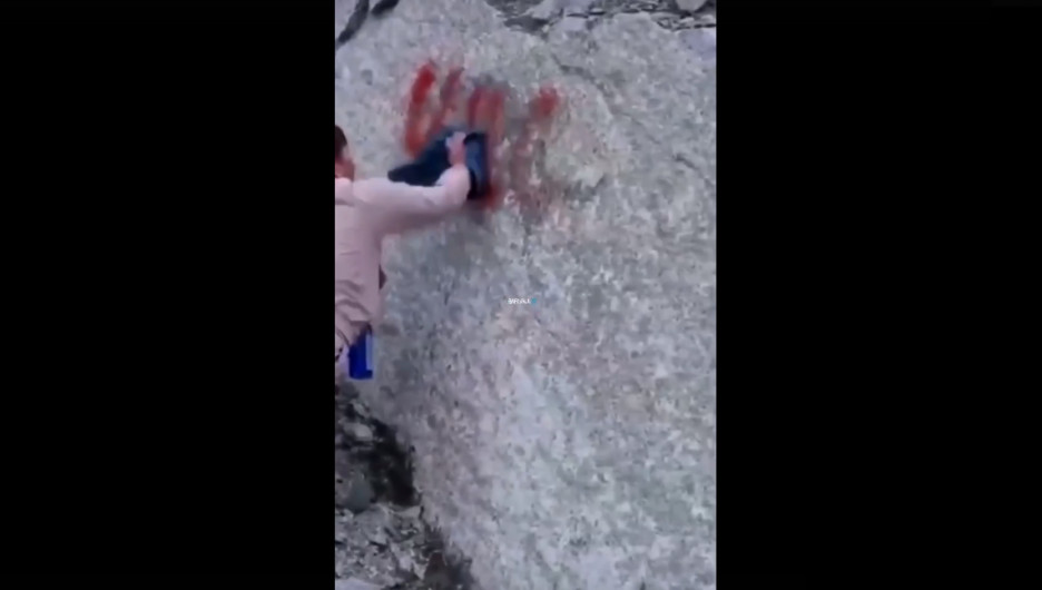 Турист отмывает надпись со скалы.