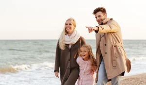 Семья гуляет по берегу моря.
