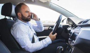 Мужчина разговаривает по телефону с использованием рук во время вождения автомобиля.