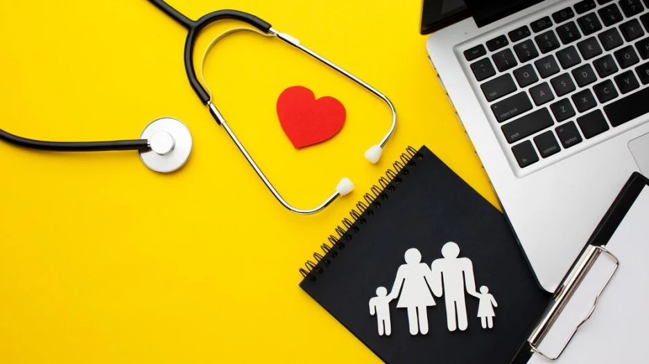 Стетоскоп, ноутбук, папка для бумаг, бумажные фигурки семьи и сердца.