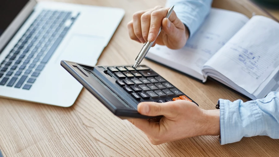 Мужчина с калькулятором, ноутбук, ежедневник.