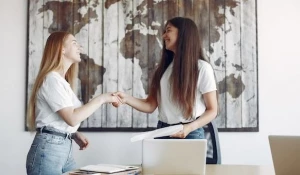 Две девушки пожимают друг другу руки.