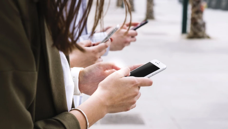 Трое человек, пользующихся смартфонами.