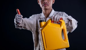 Механик с канистрой масла в руках.