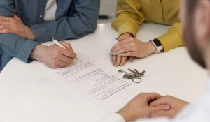 Сделка с недвижимостью. Мужчина подписывает документы.