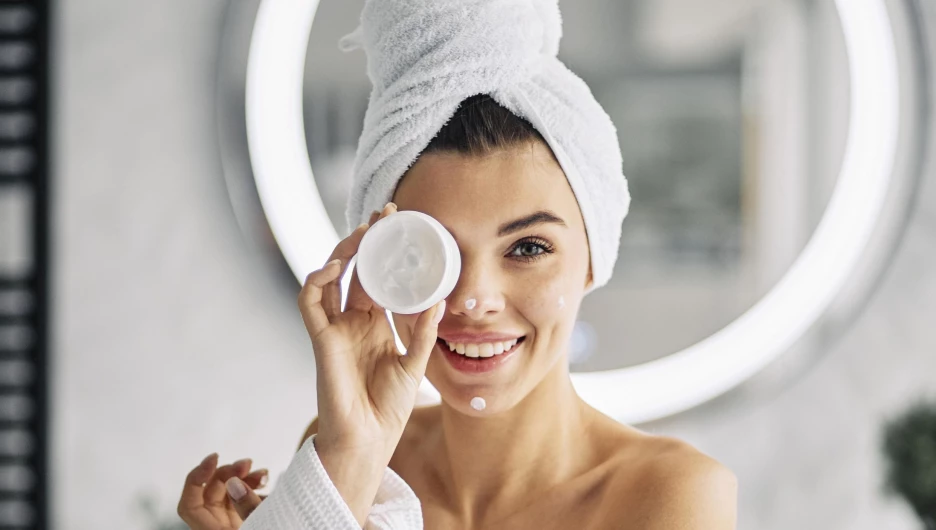 Девушка наносит крем.