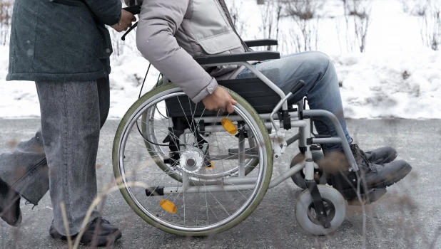 Женщина везет мужчину на инвалидном кресле.