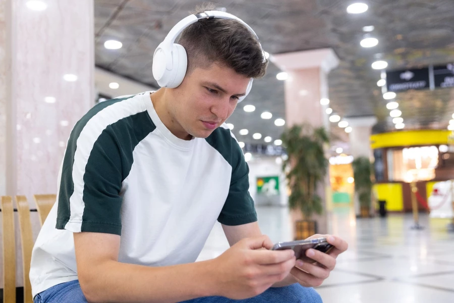 Молодой человек слушает информацию в полноразмерных наушниках.