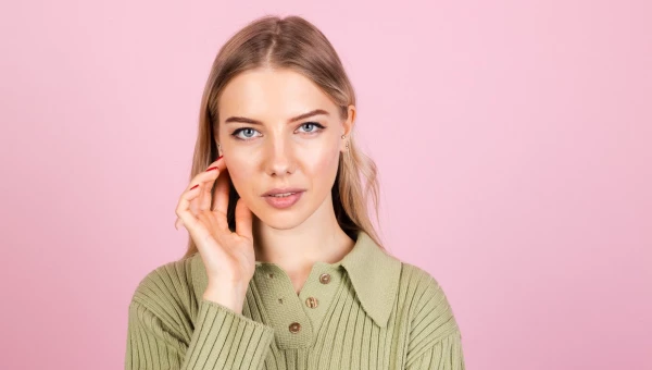 Девушка трогает лицо руками.
