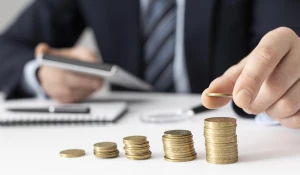 Мужчина кладет монету в столбик к другим монетам.